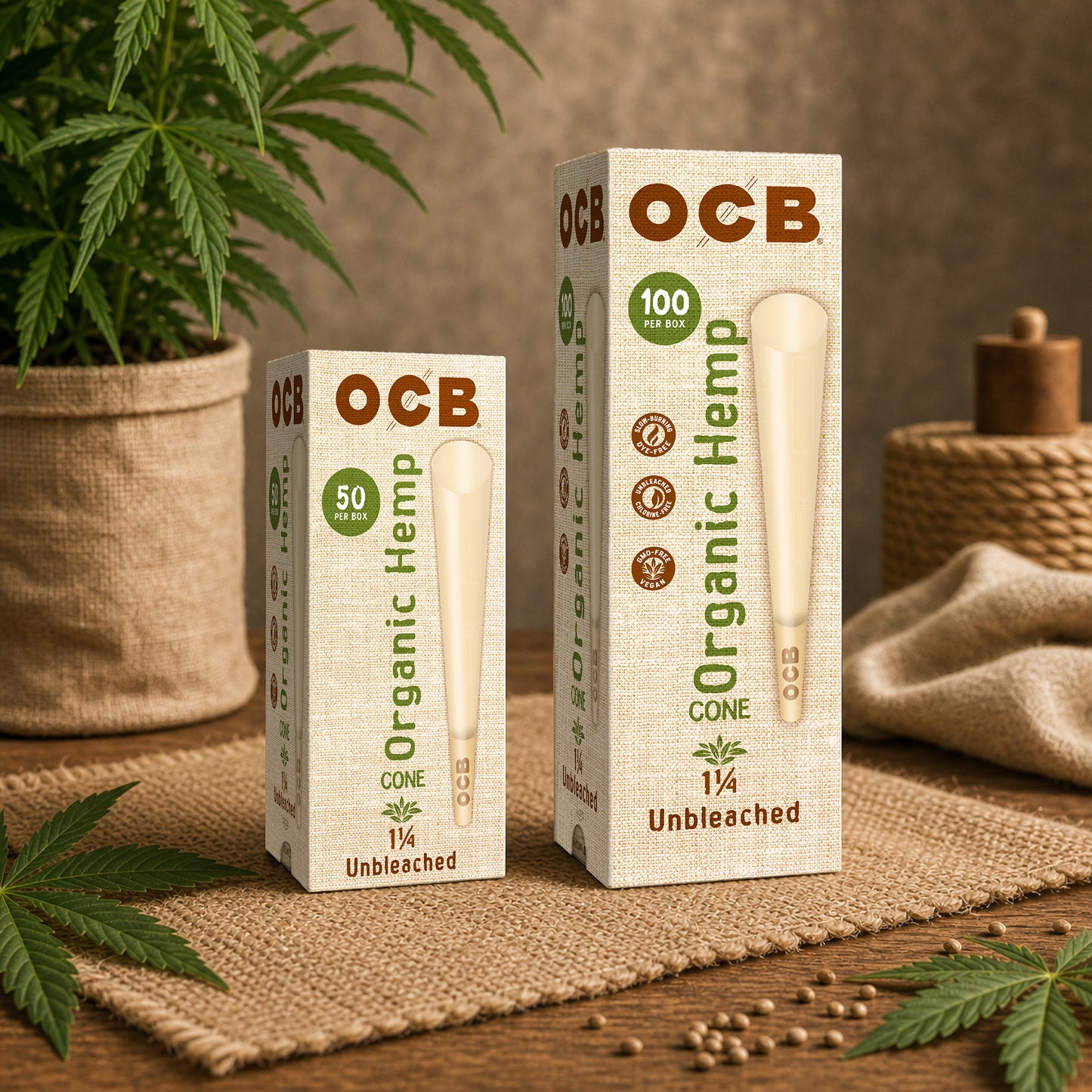 Two OCB Organic Hemp Cone packaging boxes, one 1/4 size 50 count and one 1/4 size 100 count, displayed on a rustic burlap mat with hemp leaves and a potted plant in the background.